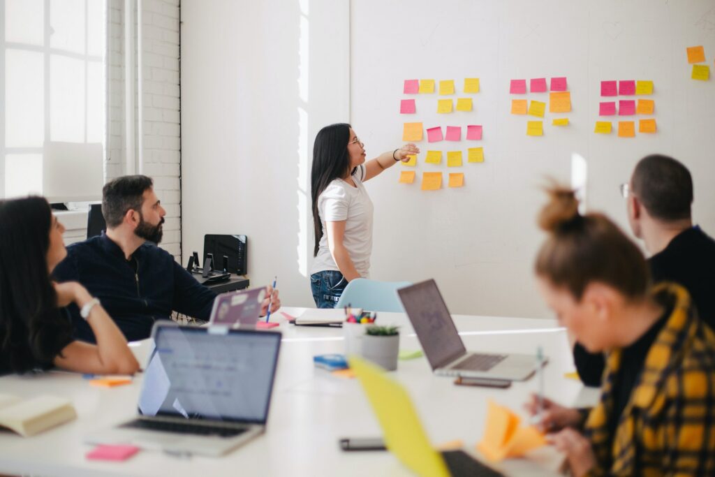 Person teaching by pointing at sticky notes on a wall