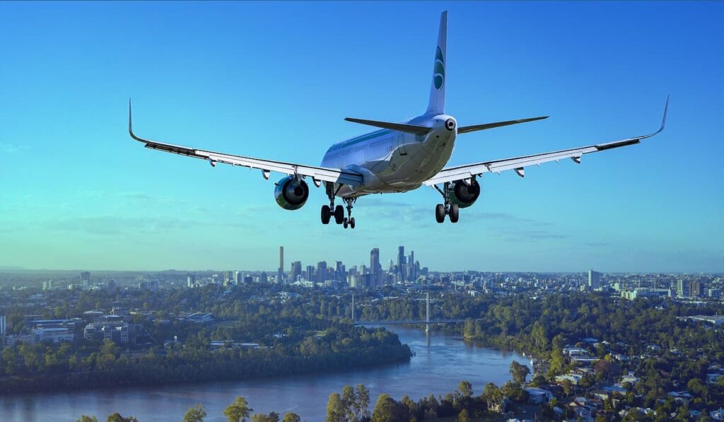 A low flying plane shot from the tail end, with a city skyline in the background