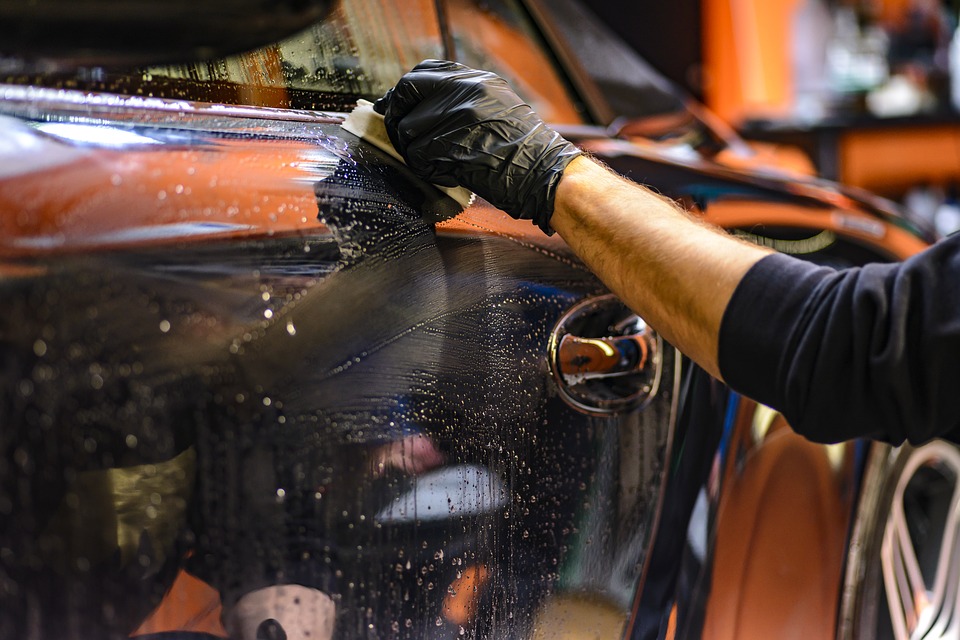 A person cleaning the outside of their car with soap and a sponge