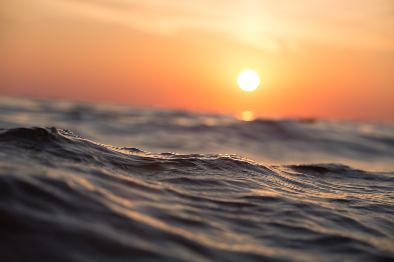 Waves in the ocean with the sun setting behind it