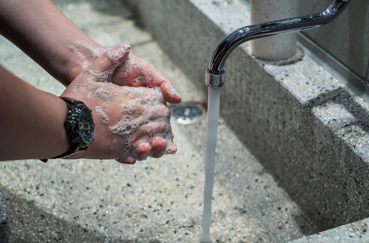 Person washing hands at a running faucet