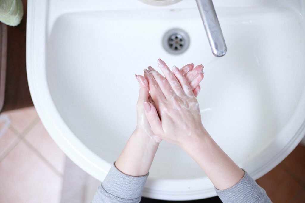 Person washing hands, lathering up soap, over a sink