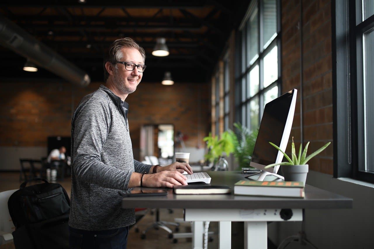 Person sitting at a shared office space using a computer.