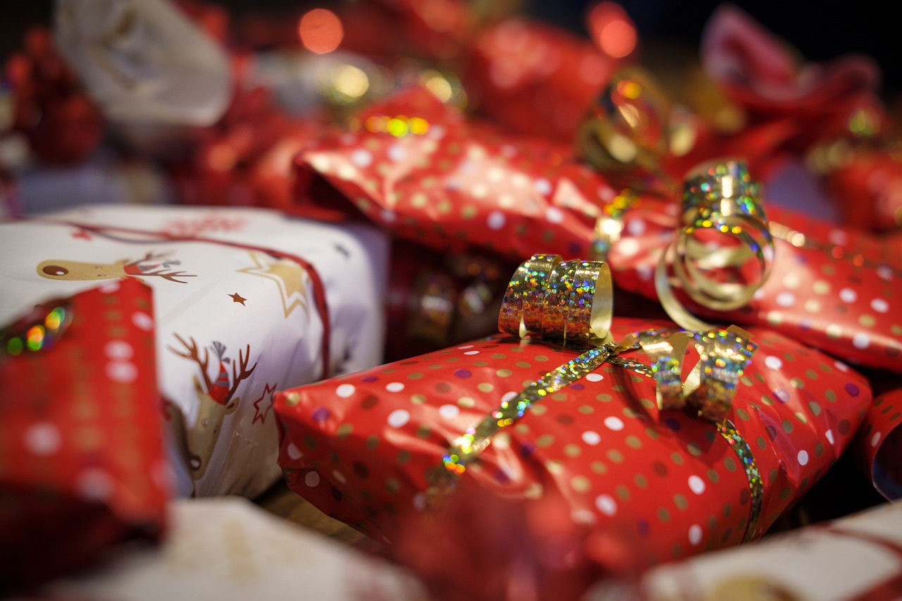 Gifts wrapped and stacked beneath a tree in gold and red.